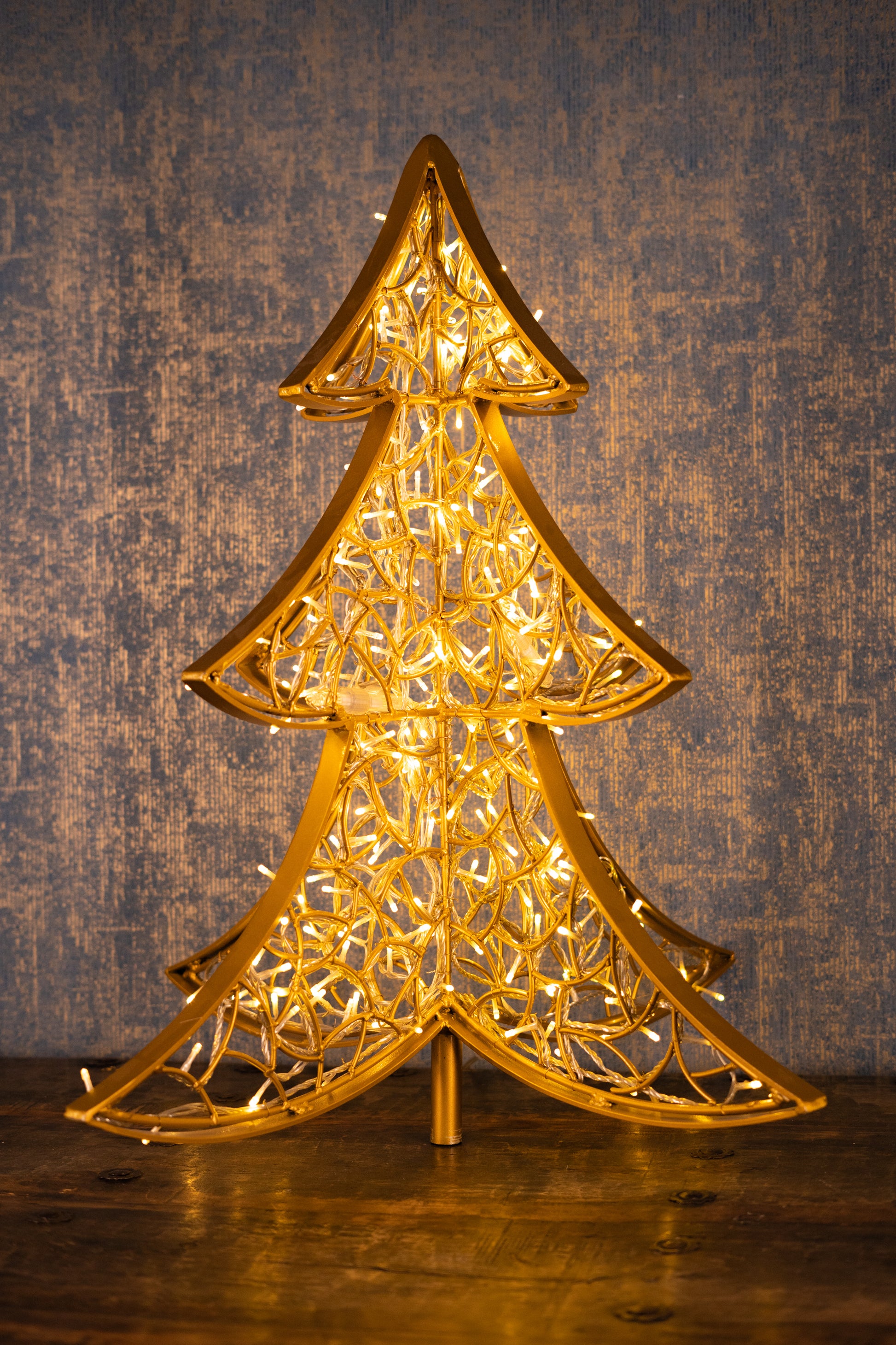 LED-Weihnachtsbaum aus goldfarbenem Aluminium, 90 cm – inszeniert vor Holzoptik für stilvolle Innenraumgestaltung